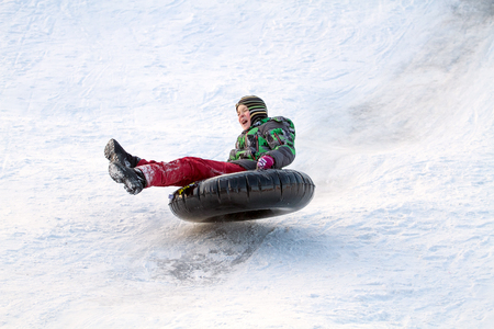 Happy boy with snow tube. Winter fun. Sliding down the hill on a snow tubeの写真素材