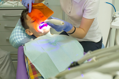 Orthodontist examining boy mouth. Orthodontist put braces on teeth. Boy afraid of dentistの写真素材