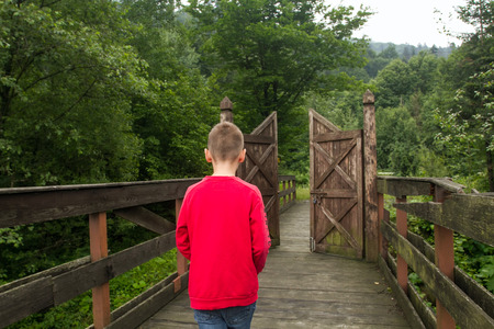 Metaphor. Growing Up Concept. Boy Goes Through the Gates to a New Life. Boy Makes a Choice. Child is Growing Upの写真素材