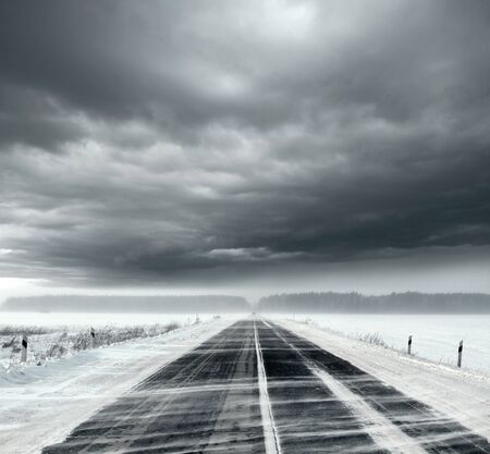 Beautiful stormy sky with clouds and snow road. Snow road in the middle of snow fieldsの写真素材