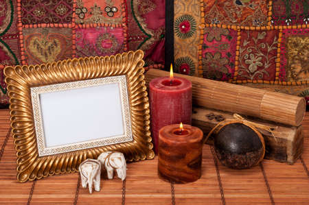 Colorful oriental table setting with picture frame, candles, elephants and wooden boxes on bambooの写真素材