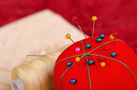 Closeup of pincushion with quilting fabrics and thread on the backgroundの写真素材