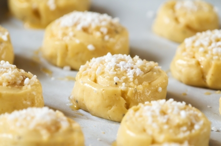 Raw sweet buns or bread rolls on a baking sheet with parchment ready for the ovenの写真素材