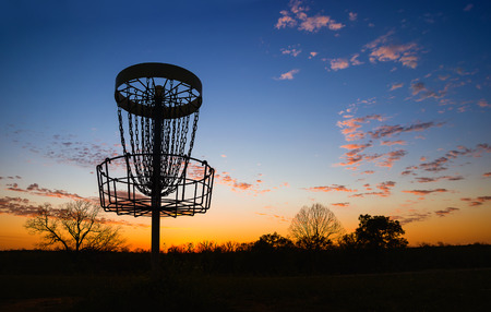 Silhouette of disc golf basket in the park at sunsetの写真素材