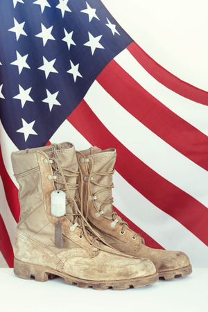 Old combat boots and dog tags with American flag in the backgroundの写真素材