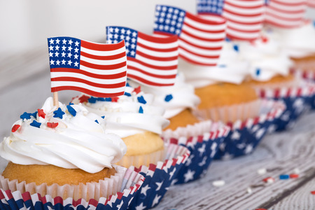 Row of patriotic cupcakes with sprinkles and American flags on vintage backgroundの写真素材