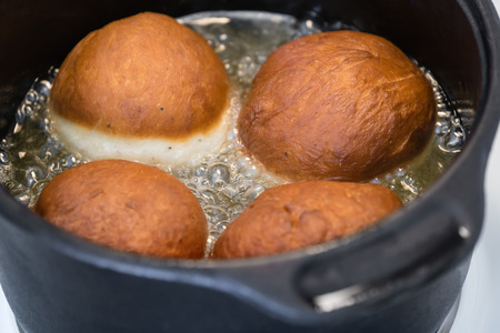 Homemade doughnuts deep-frying in oil, closeup with shallow depth of fieldの写真素材