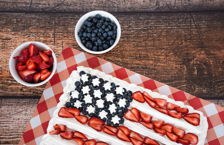 Patriotic American flag cake with blueberries and strawberries on vintage wooden backgroundの写真素材