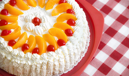Homemade cream cake with peaches and cherriesの写真素材