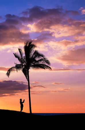 Tropical sunset with silhouettes of photographer and palm treeの写真素材