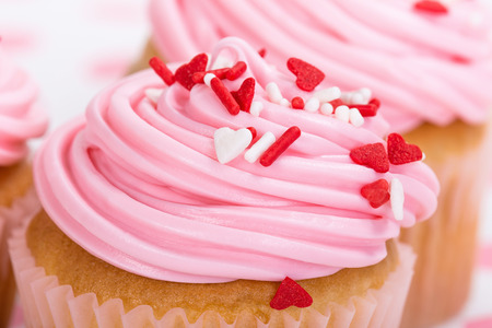 Pink Valentines Day cupcake with red and white heart shape sprinkles, close upの写真素材
