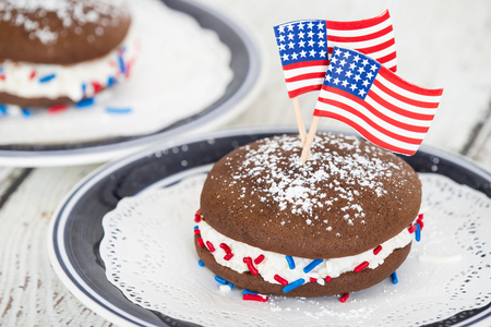 Whoopie pie or moon pie, chocolate cake dessert filled with creamy frosting. Decorated with American flags and red, white, and blue sprinkels in celebration of the 4th of July.の写真素材