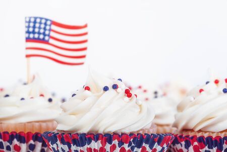 Patriotic 4th of July or Memorial Day celebration cupcakes with red, white, and blue theme sprinkles. American flag in the background, copy space.  の写真素材