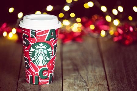 Dallas, Texas - November 4, 2021: Starbucks popular holiday beverage, served in the new 2021 designed holiday cup. Displayed on wooden rustic table against Christmas bokeh background.のeditorial素材