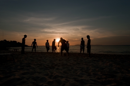 A game of football on the beach at sunsetの写真素材