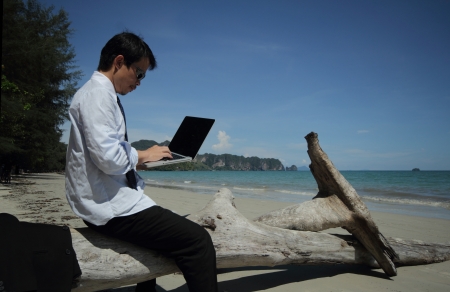 Business man sitting on a block of wood on the beach の写真素材