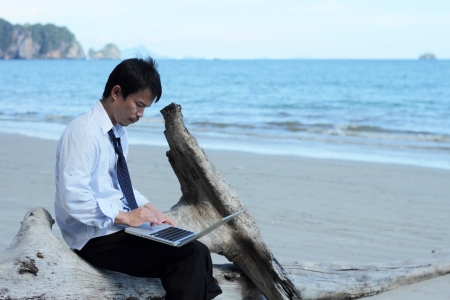 Business man sitting on a block of wood on the beach の写真素材