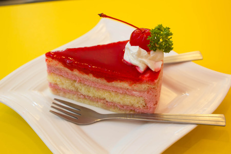 Cherry cheesecake in the white plate and yellow background