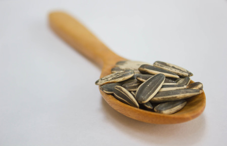 Sunflower seed with wood spoon on white backgroundの写真素材