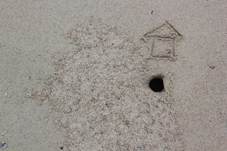House sign on sand, home icon on sandの写真素材