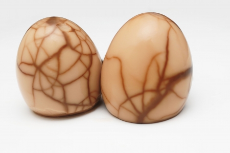 A pair of tea eggs, which are a popular Chinese delicacy infusing eggs with the essence of herbs. The patterns traced on the eggs are a result of the herbal infusion permeating the cracked shells.の写真素材