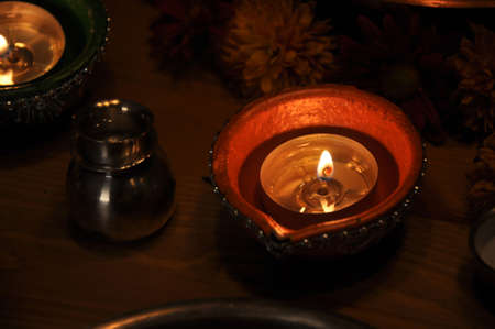 Diwali Lamp Eight - Beautiful, serene oil lamps shining in the calm of the night, surrounded by flowers & silverware.の写真素材