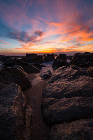 Wet rocks under a glowing sunsetの写真素材