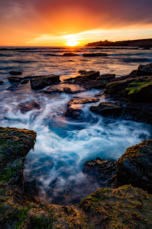 Water churning around rocks at sunsetの写真素材