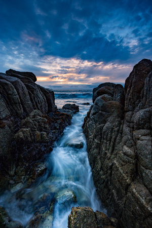 Waves rushing between rocks at sunsetの写真素材