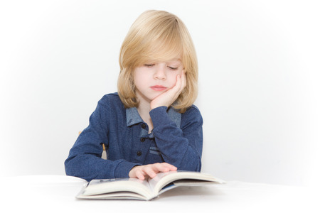 Young blonde boy reading a bookの写真素材