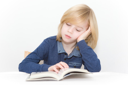 Young blonde boy reading a bookの写真素材