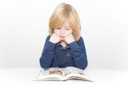 Young blonde boy reading a bookの写真素材