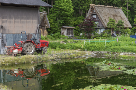Agricultural machinery, Tractor in front of warehouse and lotus pond in historic Village of Shirakawa-go in Japan in Springtimeの写真素材