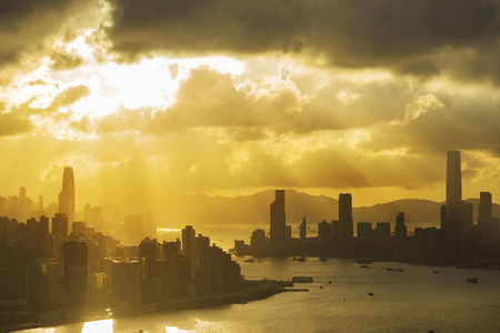 Silhouette of skyline of Hong Kong city with sun ray under sunsetの写真素材