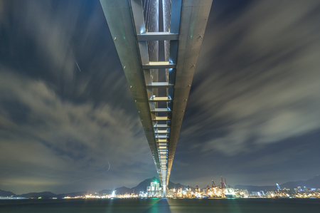 Suspension bridge and cargo port in Hong Kong city at nightの写真素材