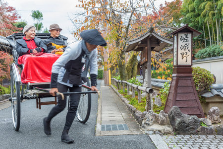 Kyoto, Japan - November 19, 2018 : Jinrikisha or Japanese rickshaw driven by male driver carrying tourist for sightseeing in Arashiyama, Kyoto in Japanのeditorial素材