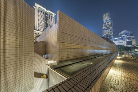 Modern pedestrian walkway and skyline of Hong Kong city at night