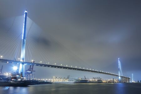 Suspension bridge in Hong Kong harbor at nightの写真素材