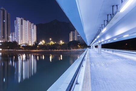 Pedestrian walkway and high rise residential building in Hong Kong city at nightの写真素材