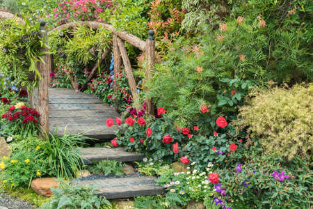 Old wooden bridge in beautiful flower garden in springtime seasonの写真素材