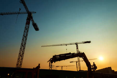 silhouette of crane and worker in construction siteの写真素材