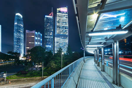 pedestrian walkway and skyscraper in Hong Kong city at nightの写真素材
