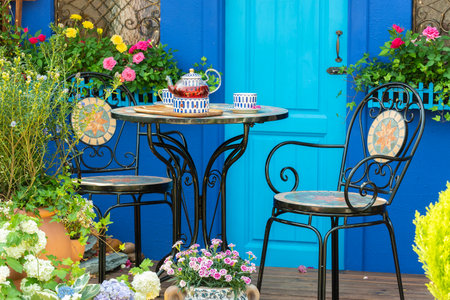porcelain set for tea or coffee on table in cozy backyard flower garden. Summer outdoor party settingの写真素材
