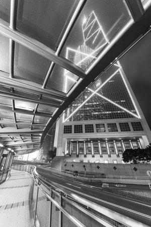 Modern pedestrian walkway and traffic in downtown of Hong Kong city at nightの写真素材