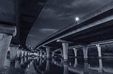 Underside of an elevated road across river at duskの写真素材