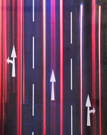 Night traffic on road. White arrow sign painted on black asphaltの写真素材