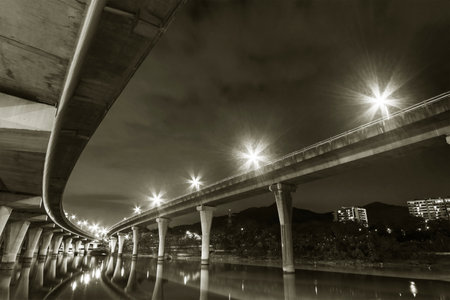 Underside of an elevated road across river at nightの写真素材