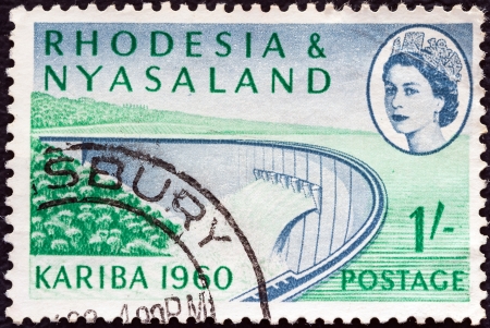 RHODESIA AND NYASALAND - CIRCA 1960: A stamp printed in Rhodesia from the "Opening of Kariba Hydroelectric Scheme" issue shows Barrage wall and Queen Elizabeth II, circa 1960. のeditorial素材