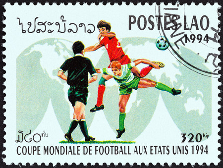 LAOS - CIRCA 1994: A stamp printed in Laos from the \"World Cup Football Championship, U.S.A.\" 4th issue shows soccer players on world map, circa 1994.のeditorial素材