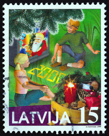 LATVIA - CIRCA 1999: A stamp printed in Latvia from the "Christmas" issue shows Children watching television, circa 1999.のeditorial素材